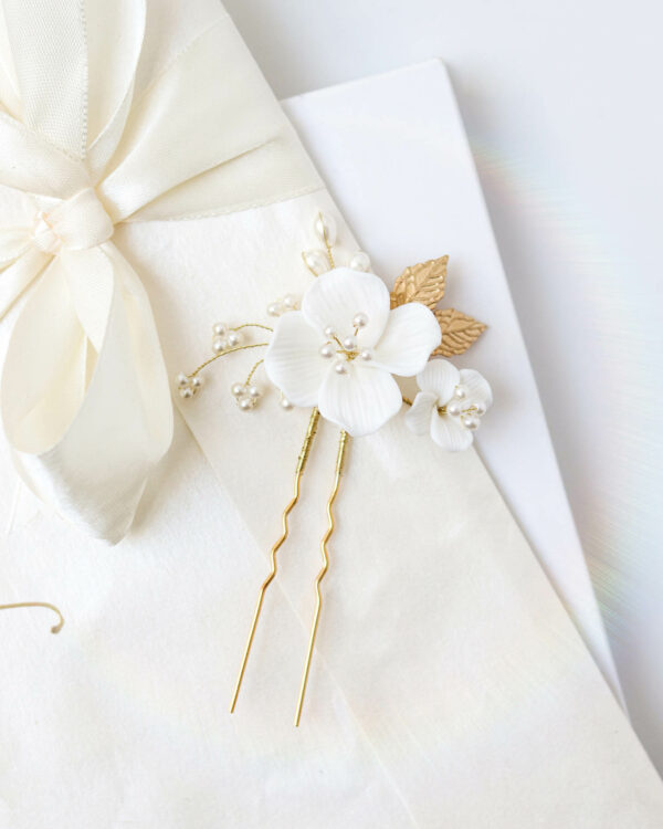 Set od dvije elegantne bijele ukoanice s porculanskim cvjetovima. Ukrašene su grančicama s biserina i zlatnim listićima. Prikladne za vjenčanja i niz svečanih frizura.